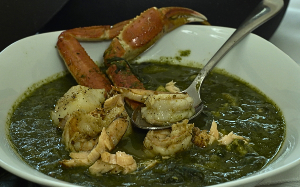 Floribbean Seafood Callaloo by Chef Winston topped with salmon, lobster, shrimp, scallops, and vibrant island greens