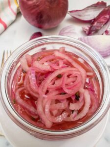Quick Pickled Red Onions in a mason jar with crisp pink onion slices made with apple cider vinegar, perfect for burgers, tacos, sandwiches, and summer BBQ recipes.